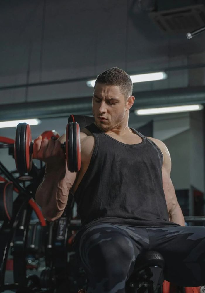 Man exercising with dumbbells in a gym setting